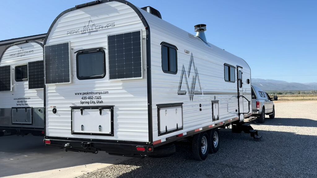 Plankis Camp #124 viewed from behind at an angle, showing the curved roofline, solar panels, and side windows.