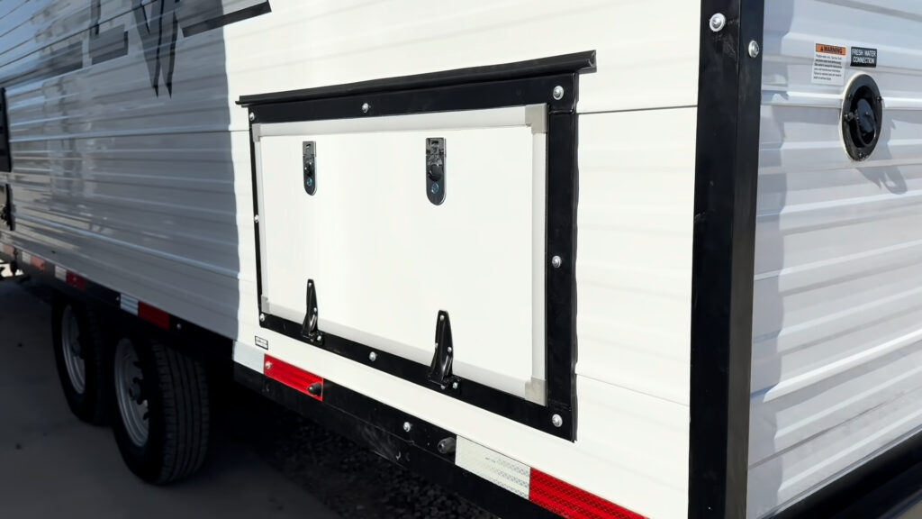 Large black-trimmed storage hatch above the tandem wheels on the road side of Plankis Camp #124.