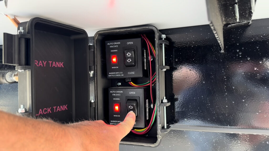 Open enclosure with separate gray and black tank waste gate controls on Plankis Camp #124.