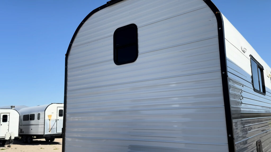 Curved white front wall with black edging and an upper bathroom window on Plankis Camp #124.