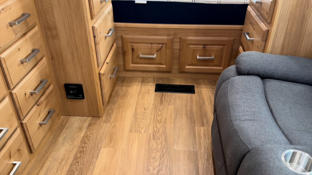 Drawers beneath the bed, wood cabinetry, a floor vent, and seating along the aisle in Plankis Camp #124.
