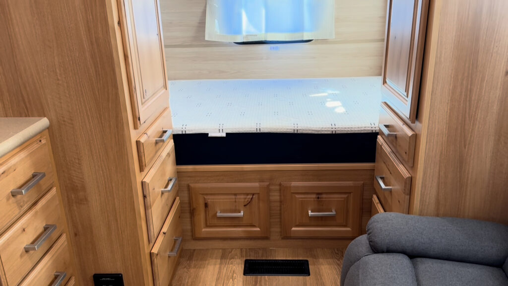 Bed and under-bed drawers between tall wood cabinets at the end of Plankis Camp #124.