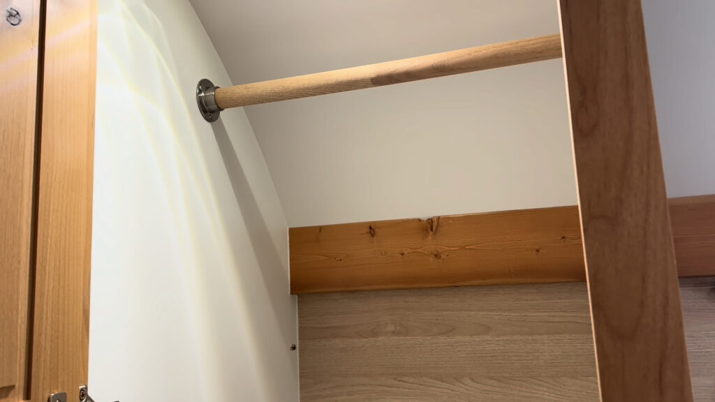 Open wood wardrobe with a hanging rod and light interior walls in Plankis Camp #124.
