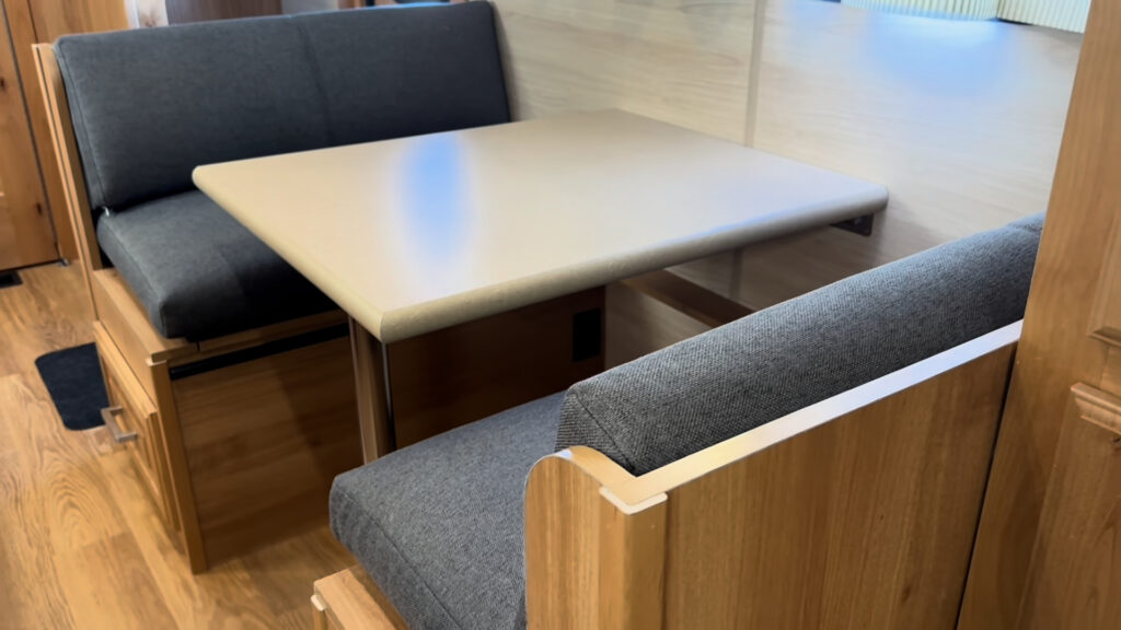 Rectangular dining table between two dark upholstered bench seats in Plankis Camp #124.