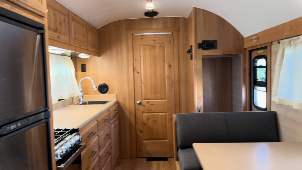 View toward the front of Plankis Camp #124 showing kitchen cabinets, refrigerator, dinette, and bathroom door.