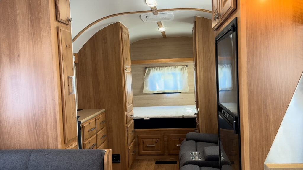 View down the aisle of Plankis Camp #124 past the dinette and refrigerator toward the bed and tall cabinets.