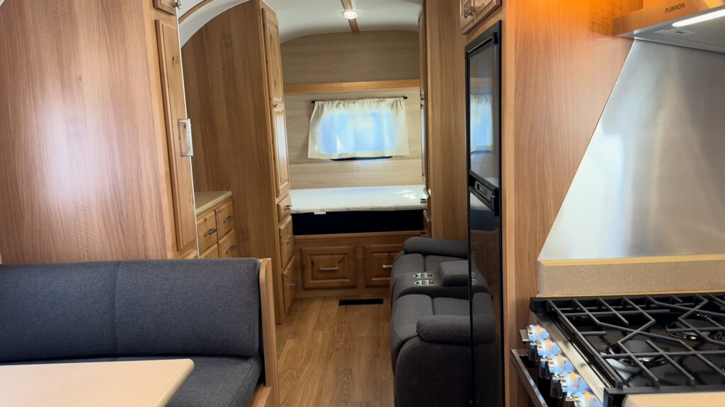 Kitchen range and dark dinette bench beside a clear aisle to the sleeping area in Plankis Camp #124.