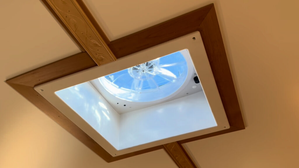 Round ventilation fan in a square ceiling opening with wood trim inside Plankis Camp #124.