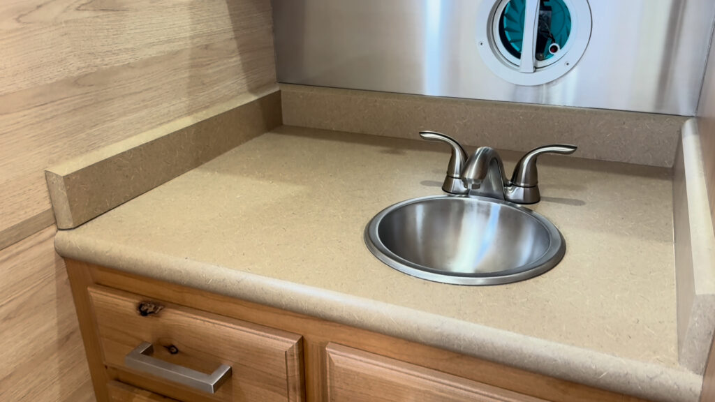 Round stainless steel sink with a two-handle faucet set into a bathroom counter in Plankis Camp #124.