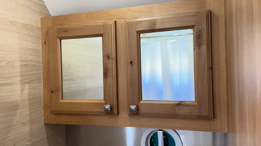 Two mirrored doors in a wood-framed bathroom wall cabinet inside Plankis Camp #124.
