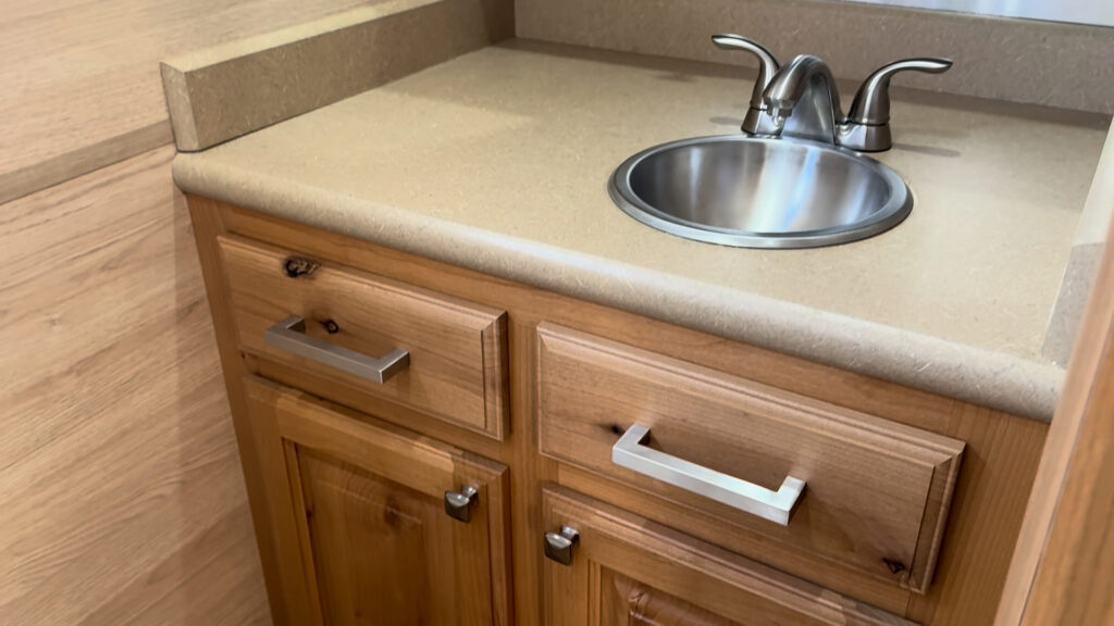 Wood drawers and cabinet doors below the round bathroom sink in Plankis Camp #124.