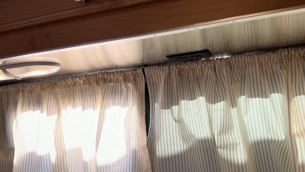 Under-cabinet lighting and outlets above striped kitchen window curtains in Plankis Camp #124.