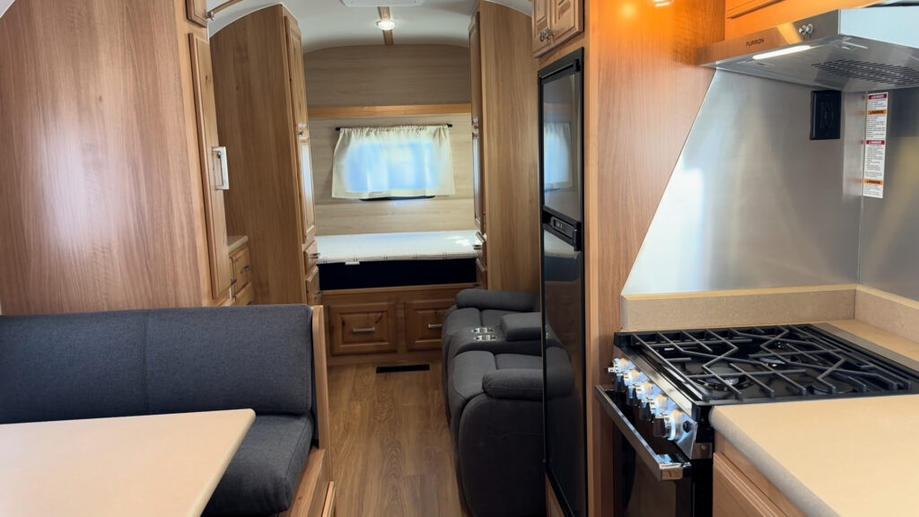 Range, refrigerator, dinette, and seating line the aisle toward the bed in Plankis Camp #124.