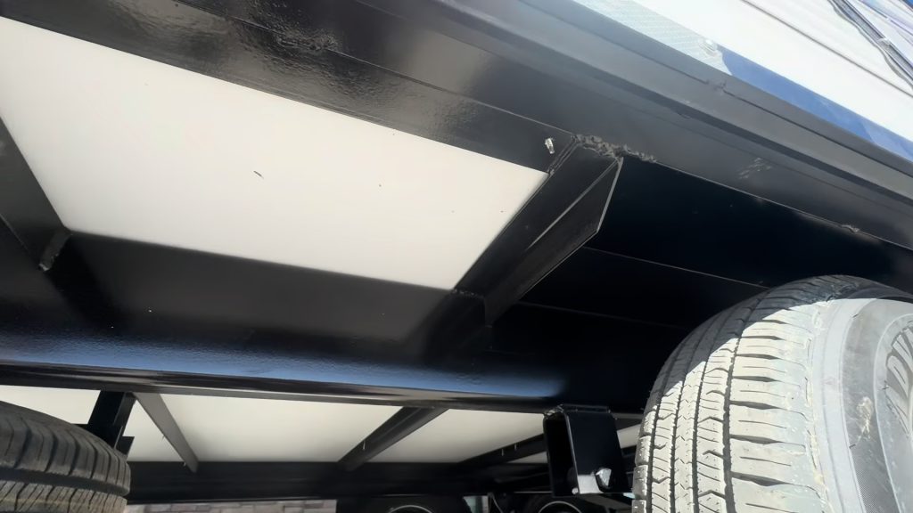 Close view of the protected wheel well and underbody structure beside a tire.
