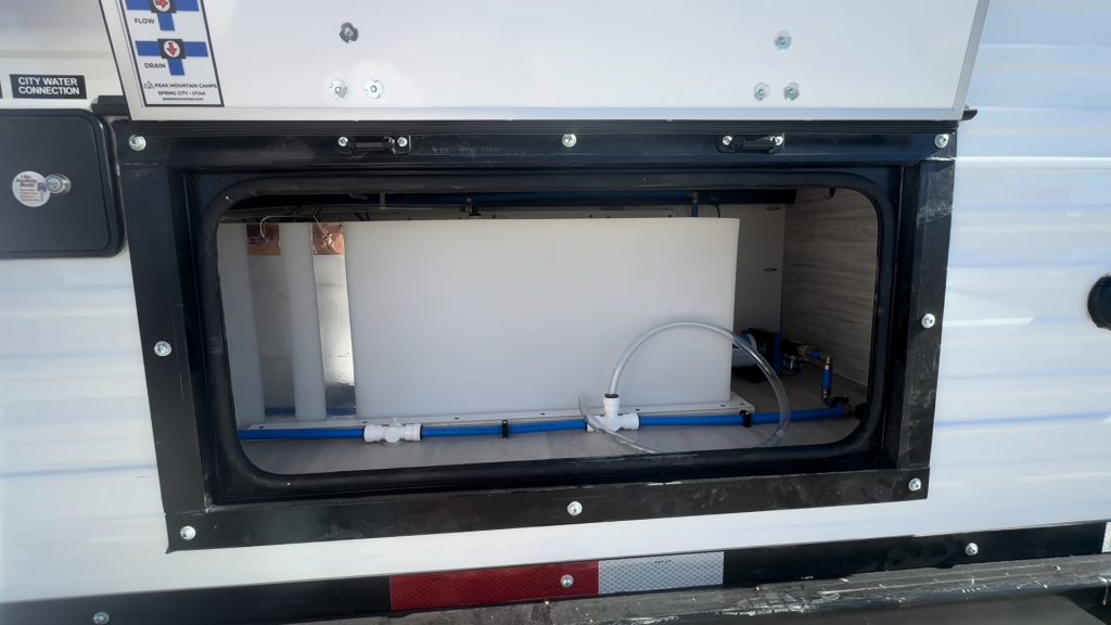 Open rear service compartment showing water lines and access space.