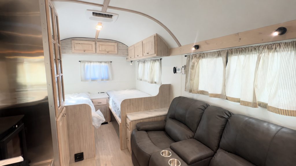 Two Twin XL beds at the back of the camp, with a reclining sofa in the foreground.