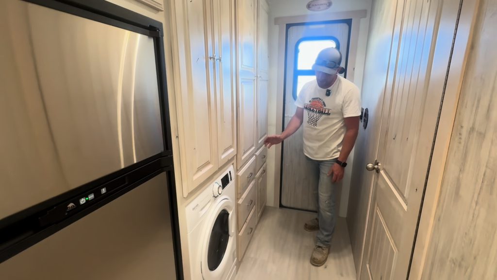 Washer dryer combo installed beside the entry hallway cabinets.