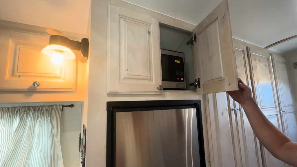 Microwave cabinet above the elevated refrigerator in the kitchen.