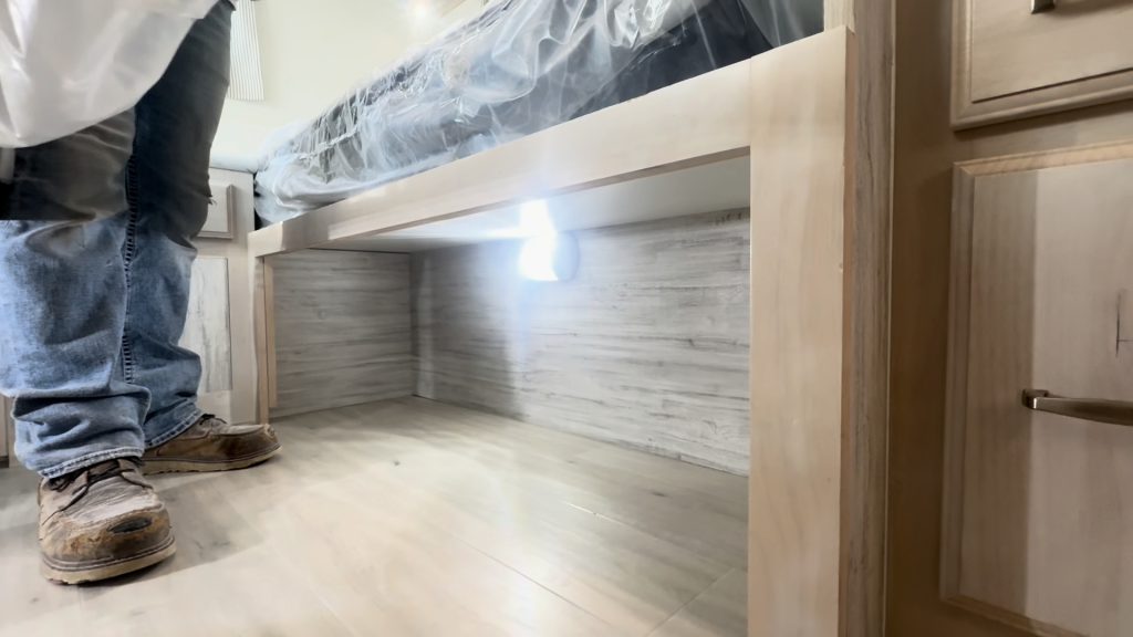 Open lighted storage space beneath one of the Twin XL beds.