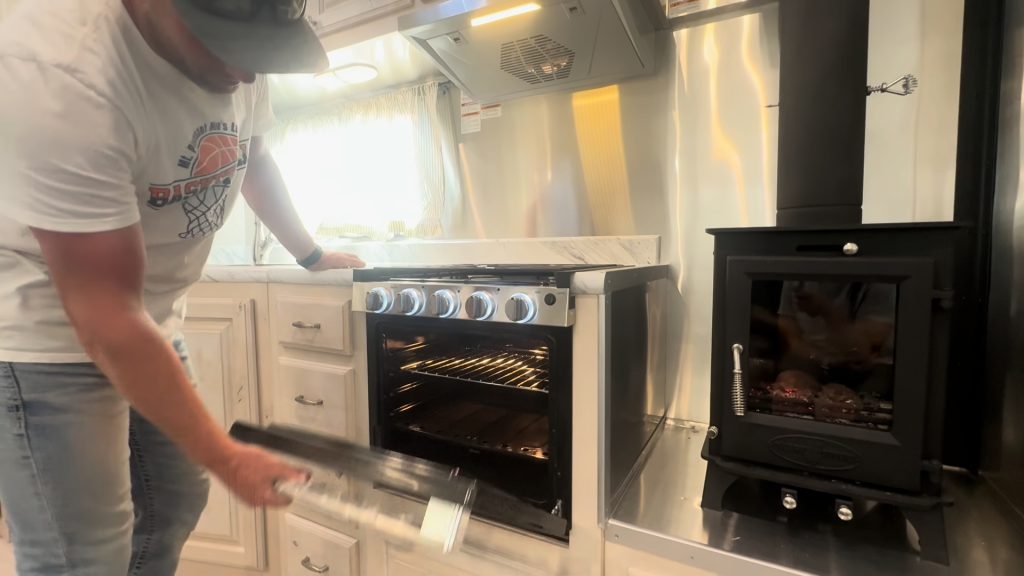 Presenter demonstrating the oven next to the wood-burning stove.