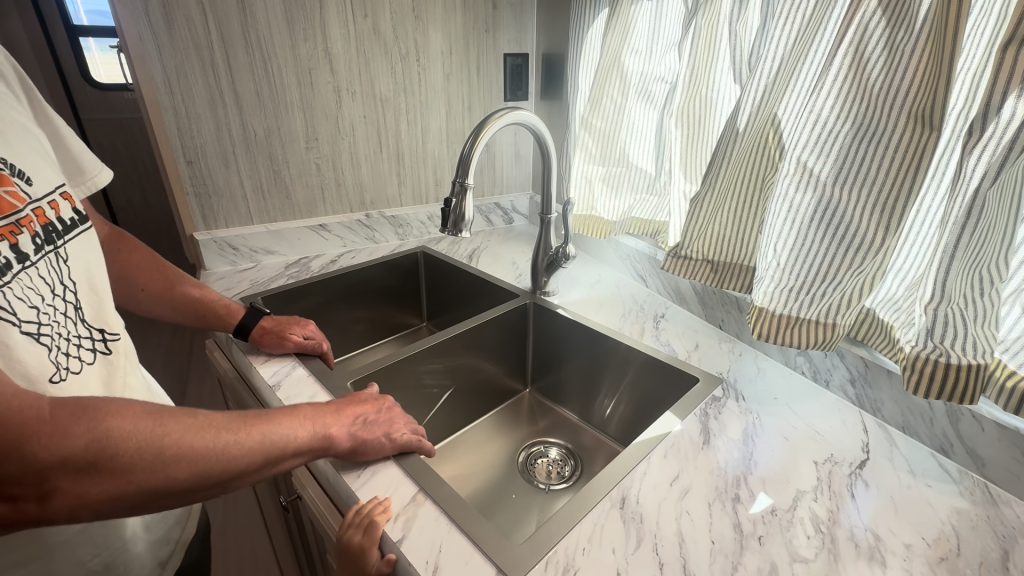 Close view of the stainless steel double sink and faucet beneath the kitchen window.