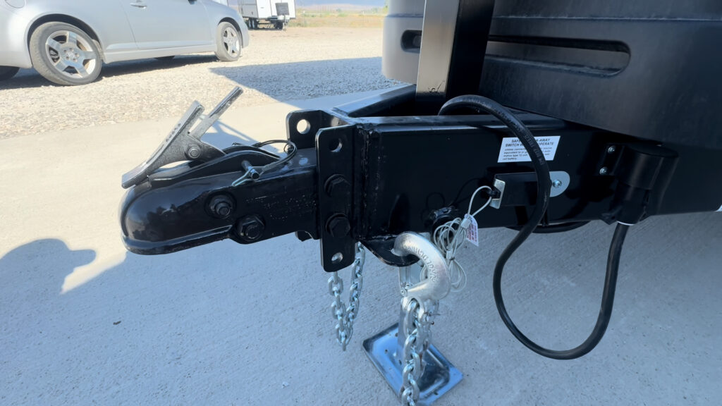 Close view of the Kendall Camp adjustable coupler, hitch assembly, safety chains, and electrical cable.