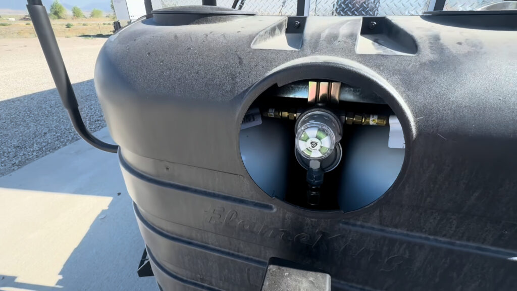 Close view through the propane cover opening showing the regulator and connection inside.