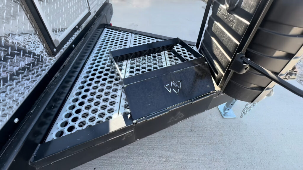 Open metal storage hatch built into the perforated Kendall Camp tongue deck.