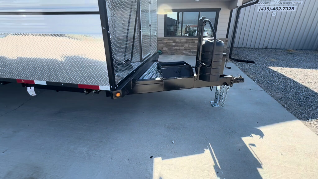 Front side view of the Kendall Camp showing the tongue deck, storage hatch, propane cover, hitch, and jack.
