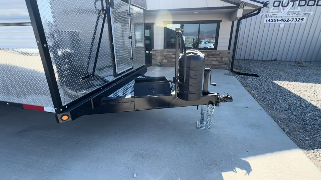 Front exterior view of the Kendall Camp tongue with the propane cover, hitch, jack, and storage hatch.