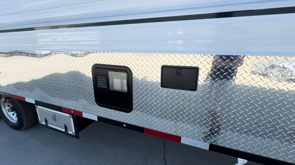 Side view of the Kendall Camp diamond-plate lower panel with two utility openings above a storage box.
