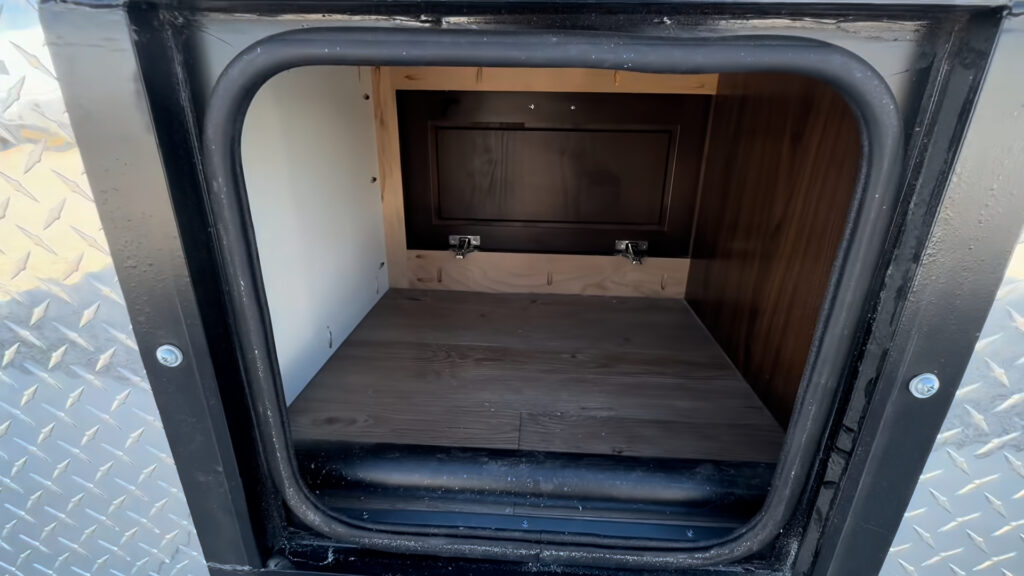 Open Kendall Camp side compartment with a finished floor and an inner access panel.