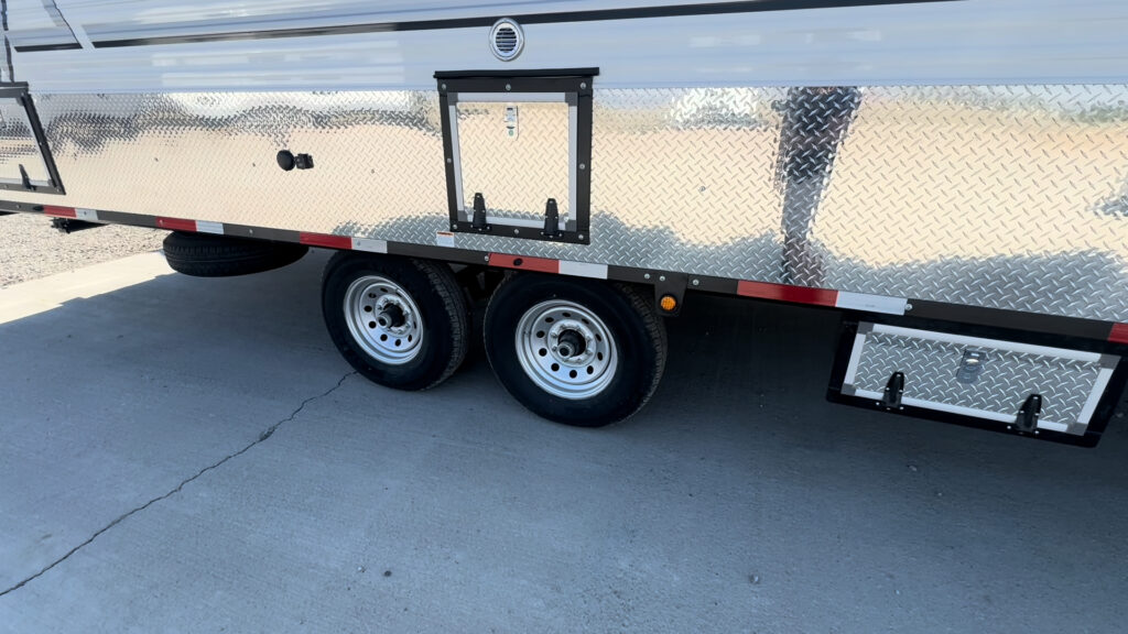 Side view of the Kendall Camp tandem wheels, exterior access hatch, and under-frame storage box.