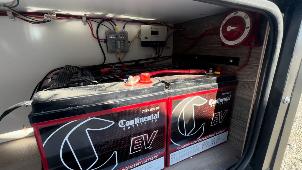Open Kendall Camp exterior compartment showing deep-cycle batteries and electrical wiring.