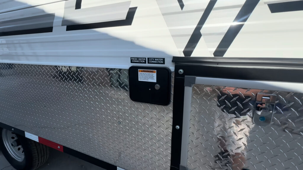 Close view of the labeled city-water connection and adjacent exterior utility opening on the Kendall Camp.