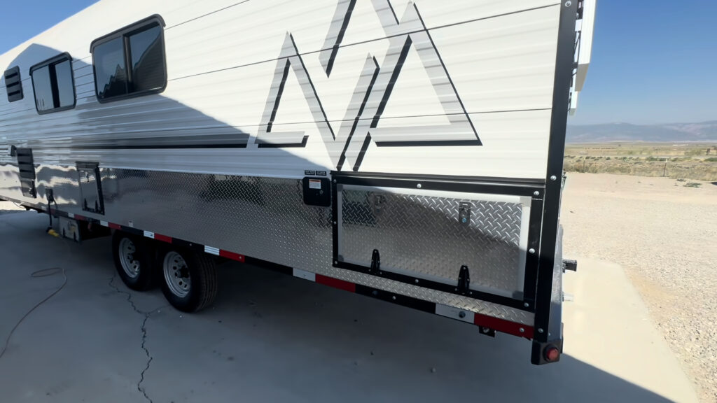 Long side view of the Kendall Camp with windows, diamond-plate wrapping, and exterior storage hatches.
