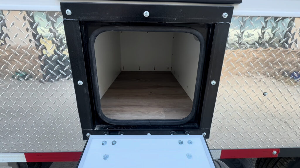 Open rectangular side storage compartment within the Kendall Camp diamond-plate lower panel.