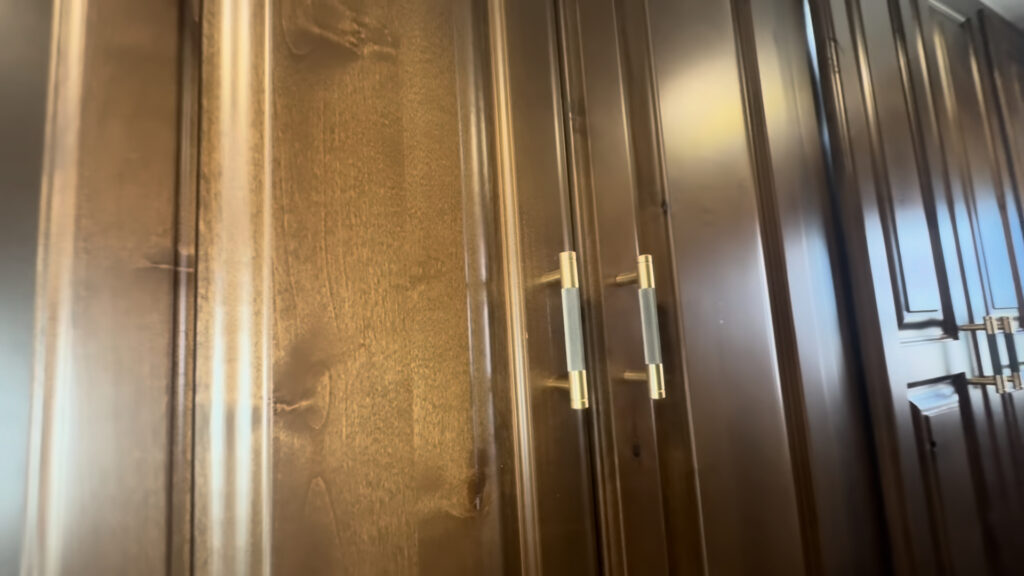 Close view of tall dark hardwood closet doors and metal pulls inside the Kendall Camp.