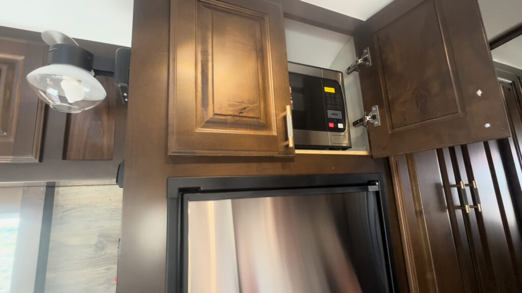 Interior view of the Kendall Camp refrigerator with a microwave cabinet and hardwood storage above it.