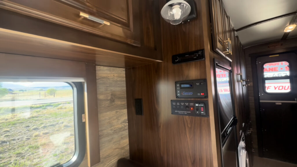 Interior view of the Kendall Camp wall-mounted controls beside a window, hardwood cabinets, and the front door.