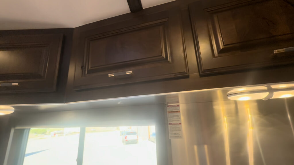 Interior close view of Kendall Camp overhead hardwood cabinet doors and under-cabinet lights.