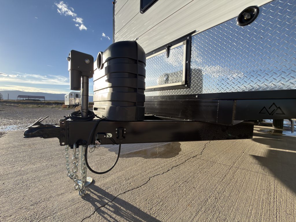 Side view of the hitch, jack, propane cover, and diamond-plate front wall in Keulen Camp #132.