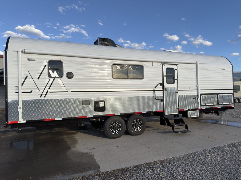 Full side view with windows, entry door, Peak graphics, and tandem wheels in Keulen Camp #132.