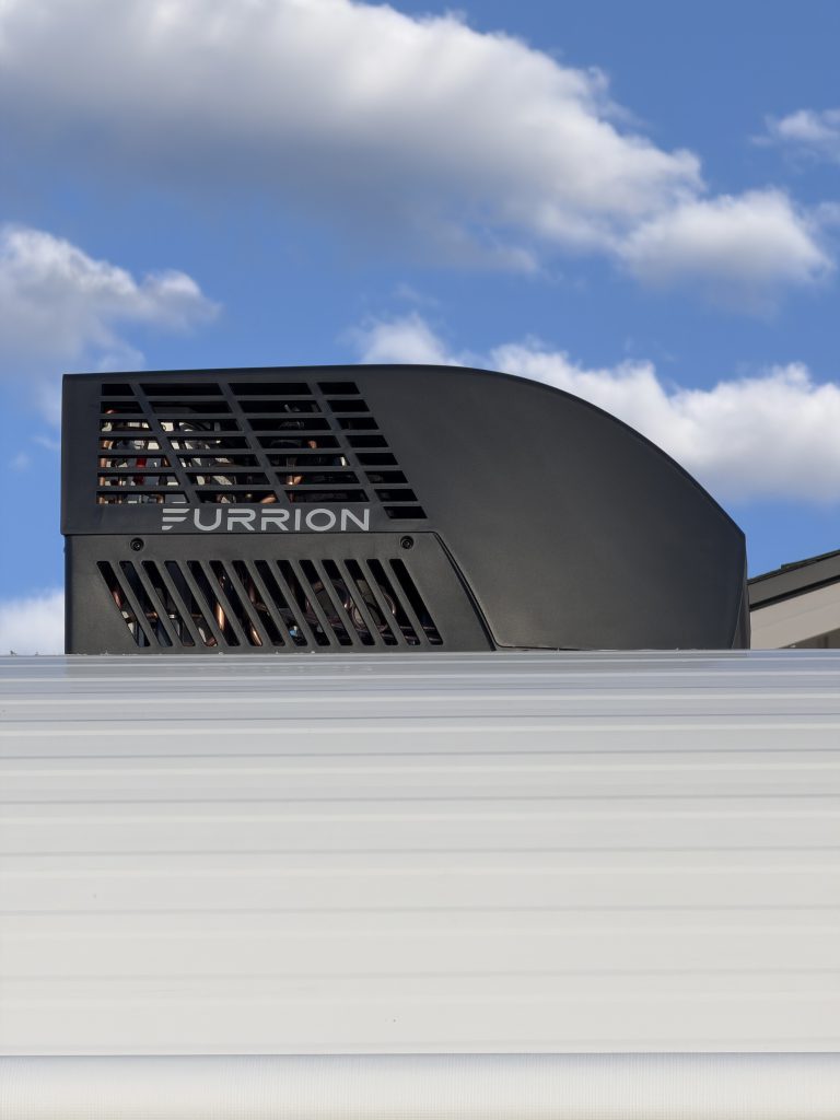 Furrion roof-mounted air conditioner above the white siding in Keulen Camp #132.