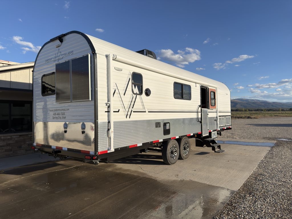 Front angle showing the curved roofline, windows, hitch, and tandem wheels in Keulen Camp #132.