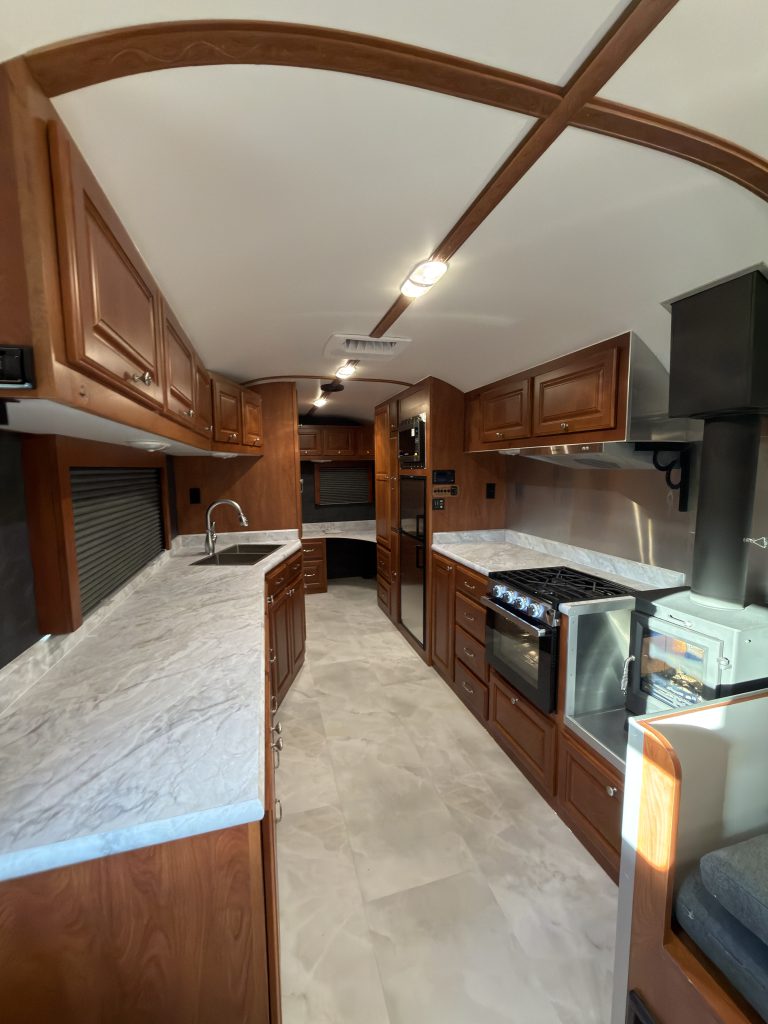 Long countertop facing the kitchen cabinets, range, and refrigerator in Keulen Camp #132.