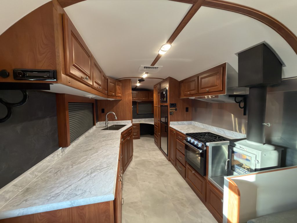Wide interior view of the countertop, range, refrigerator, and overhead cabinets in Keulen Camp #132.
