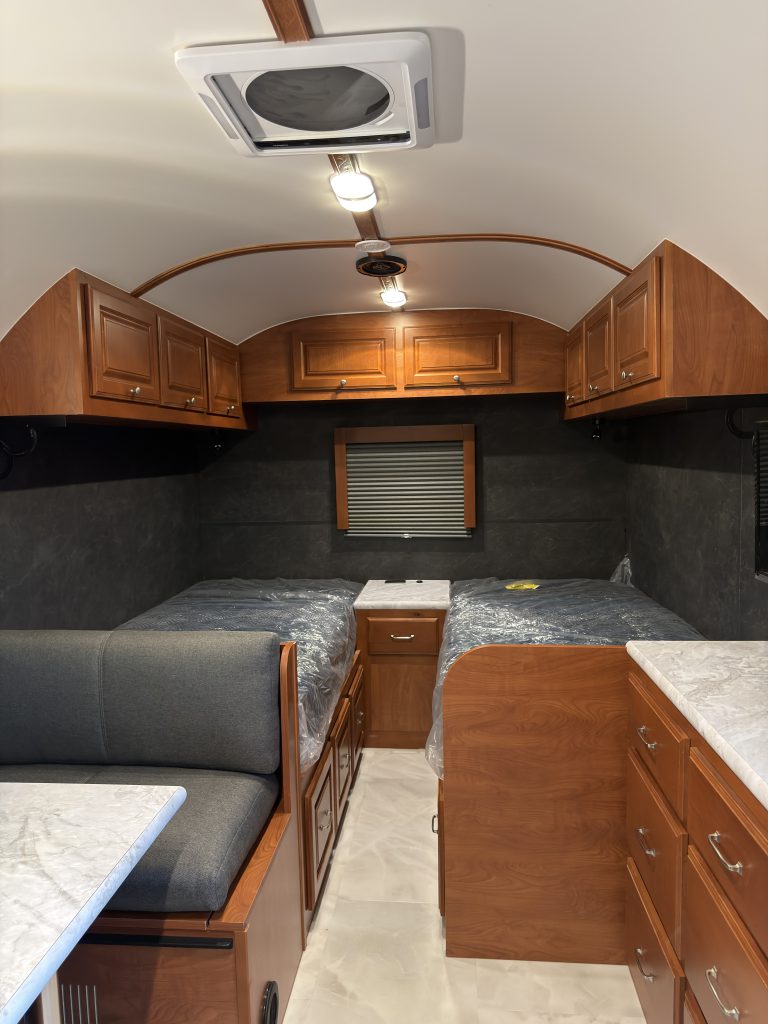 Twin mattress platforms with a central nightstand and overhead storage in Keulen Camp #132.