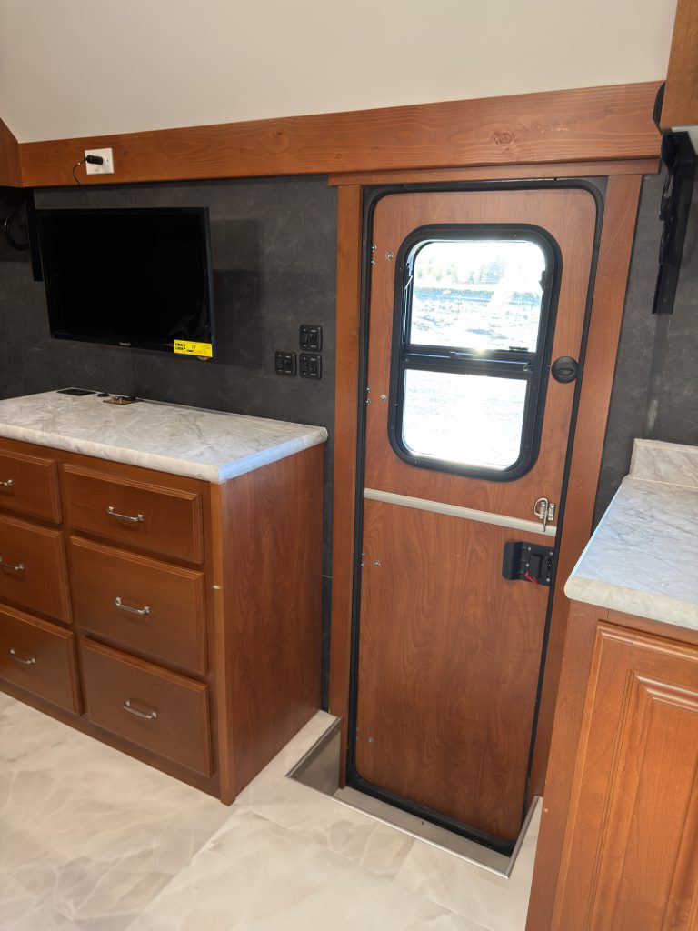 Wood-trimmed entry door beside the media cabinet and drawers in Keulen Camp #132.
