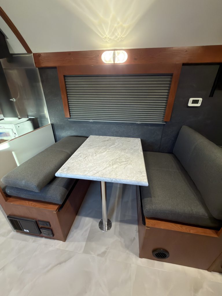 Dinette table between cushioned seats beneath a window in Keulen Camp #132.
